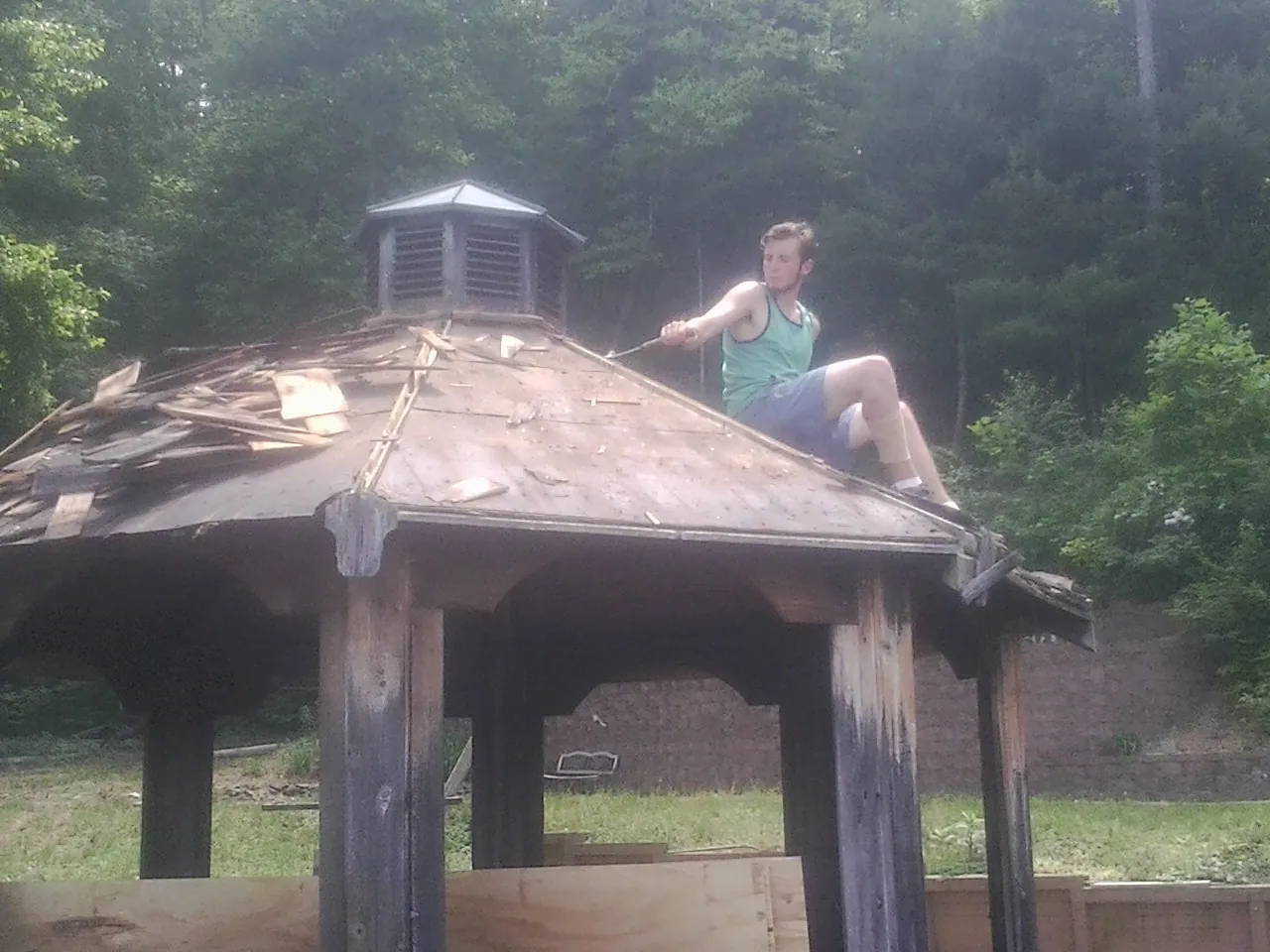 Tearing the old roof off a wooden gazebo before new shakes in Lebanon